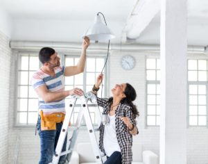 Couple helping each other replace a lamp of the house