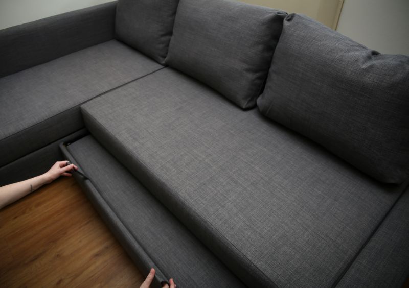 a woman converting a gray sofa to bed