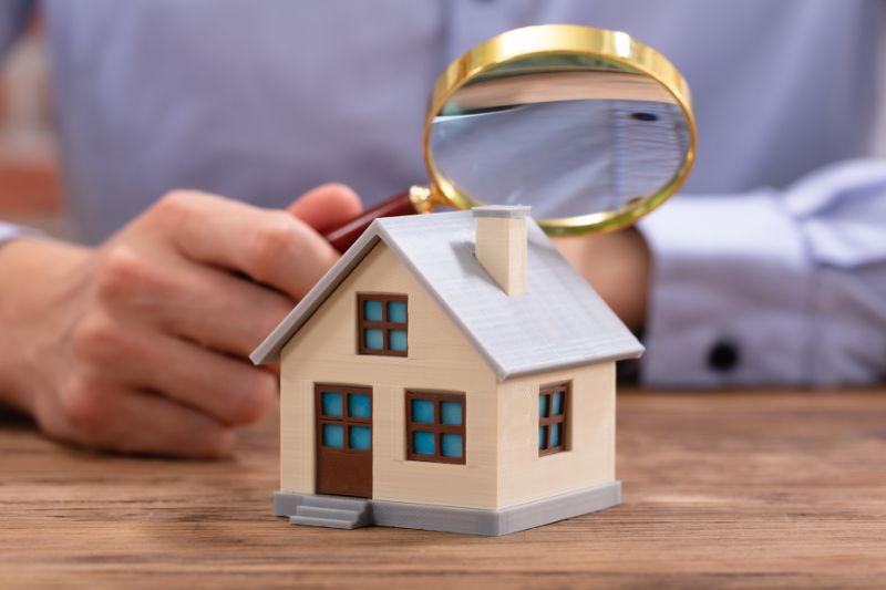 a man inspecting a miniature house using a magnifying glass